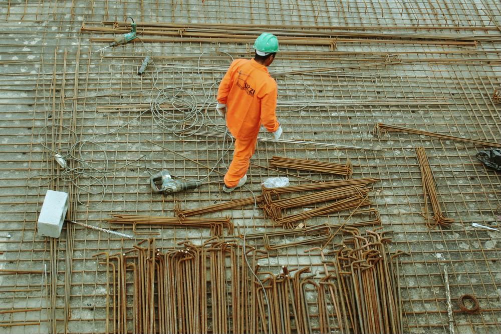 Imagem superior de um trabalhador da construção civil analisando uma obra