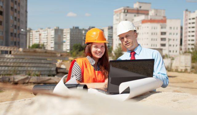 imagem de um homem e uma mulher em uma construção, olhando em um noteboo.