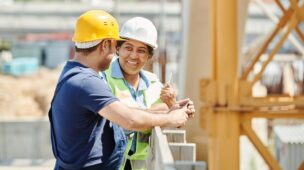 Homem e mulher com equipamentos de construção civil conversando em uma obra