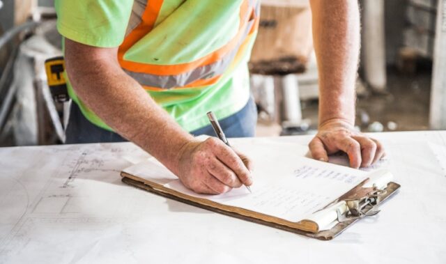Profissional preenchendo relatório de obras diário no canteiro de construção